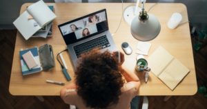 Woman has virtual class with notebooks sprawled out on desk